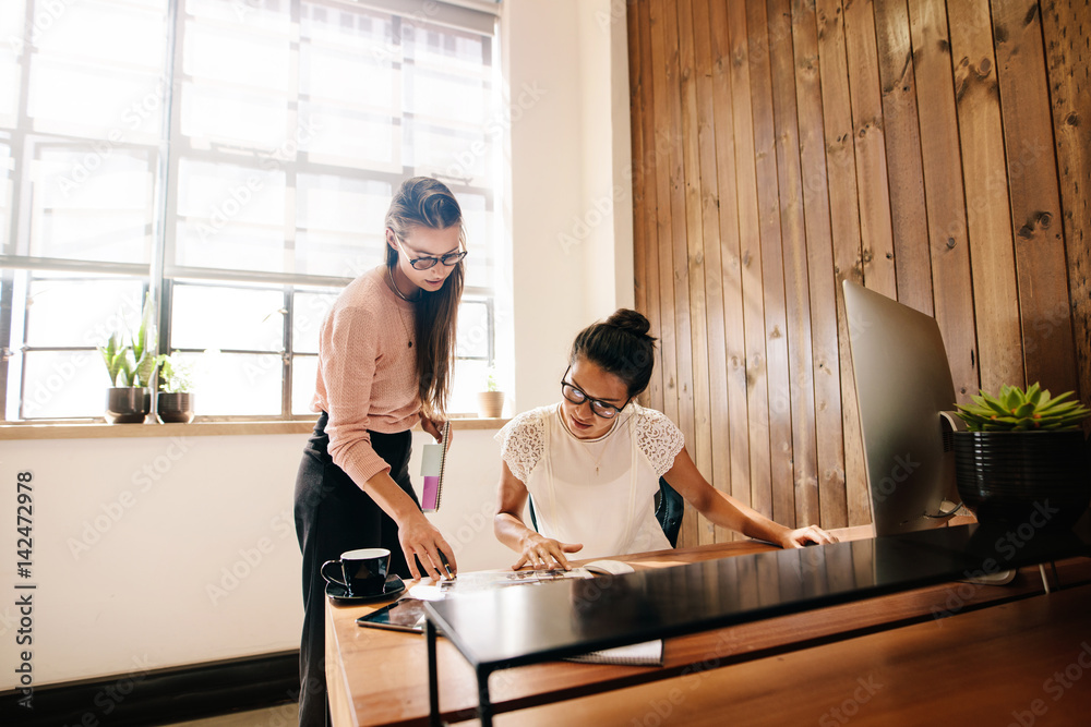 Two business women reading documents on desk Two business women reading documents on desk
