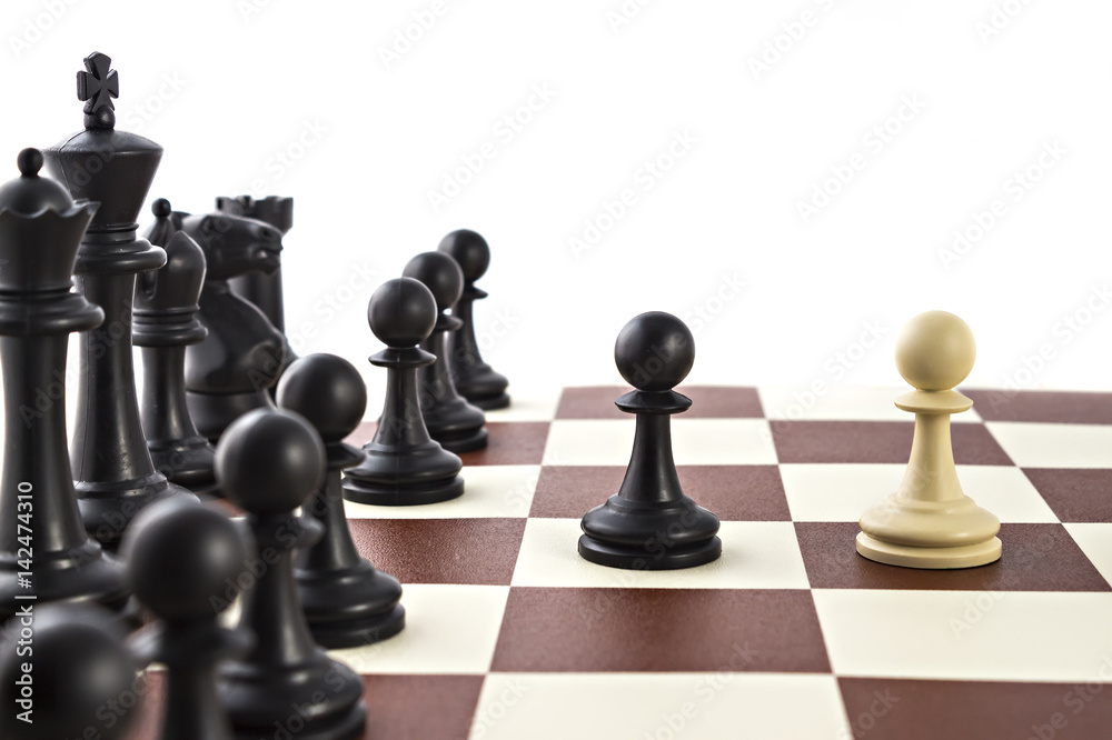 Chess business concept, leader & success. White pawn is challenging black pawn in front of black figures on chess board Chess business concept, leader & success. White pawn is challenging black pawn in front of black figures on chess board