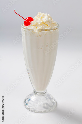 milk cocktail with a cherry in a tall glass