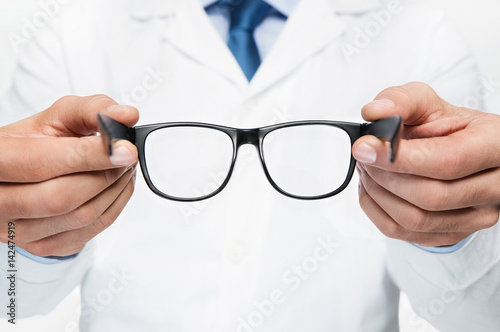 Close up of doctor oculist, optometrist holding new eyeglasses