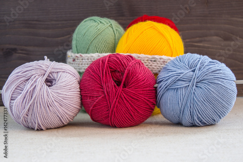 Multi-colored balls of yarn on a dark wooden background. Selective focus.