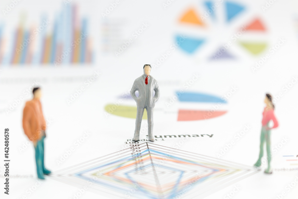Miniature figures businessman standing on a graph chart Miniature figures businessman standing on a graph chart