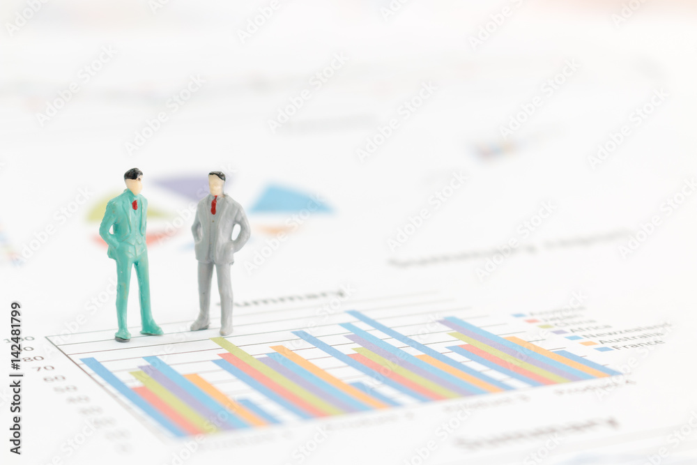 Miniature figures businessman standing on a graph chart Miniature figures businessman standing on a graph chart
