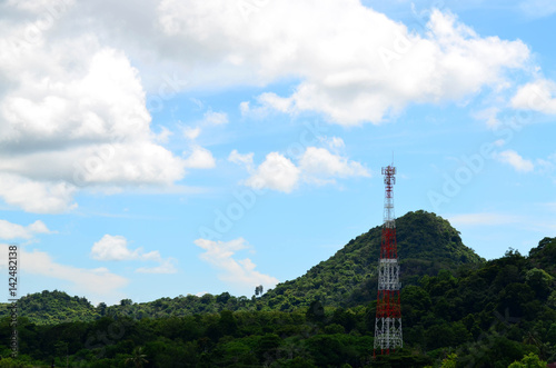 Telecommunication tower against blue sky and mountain © ubonwanu