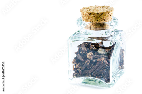 Dry cloves in glass bottle isolated on white background. Closeup macro shot.