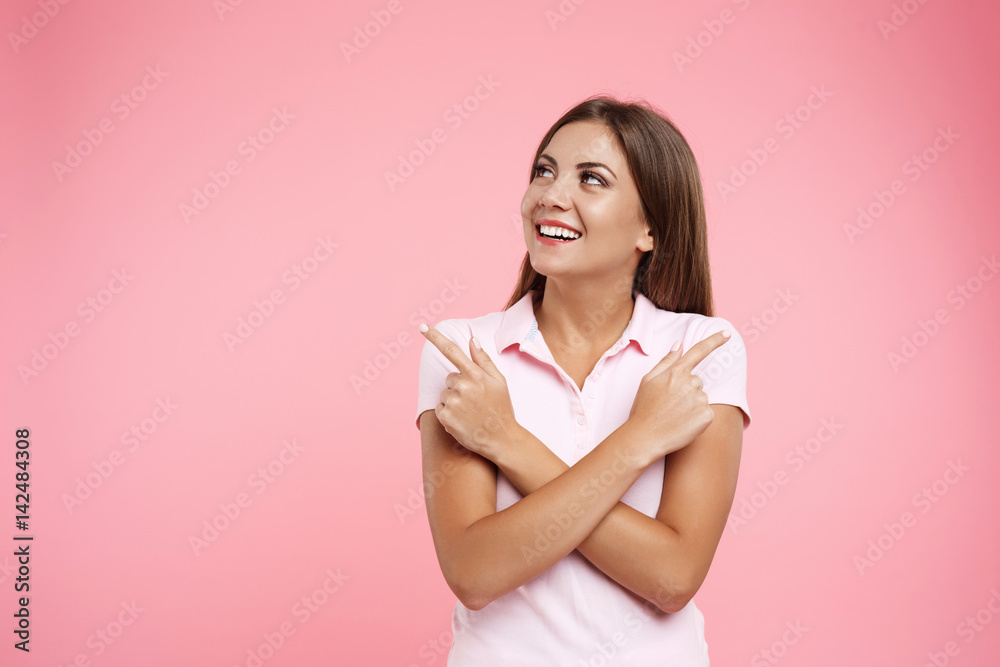 Smiling girl in pink sportswear looking away with hands across Smiling girl in pink sportswear looking away with hands across