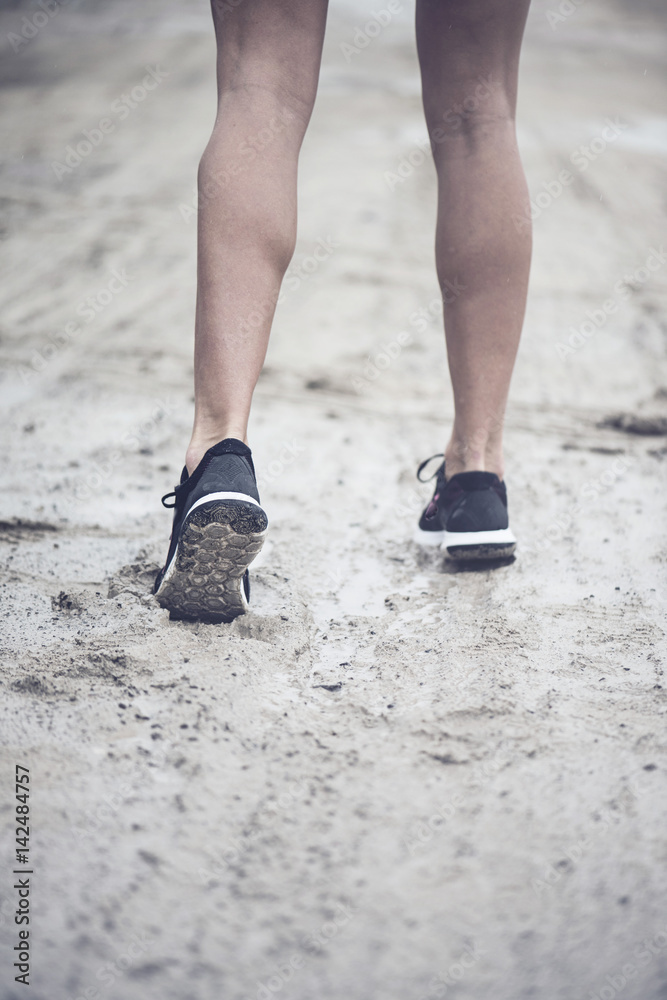 Close up of a pair of strong athletic legs running position in the mud on a rainy day Close up of a pair of strong athletic legs running position in the mud on a rainy day