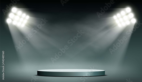 Round podium illuminated by searchlights.
