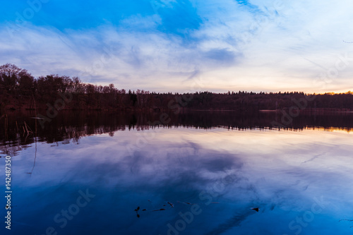 Calm rural lake reflecting an early sunset