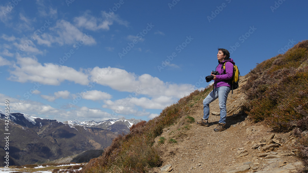 Hiker with camera and backpack taking picture of beautiful mountain