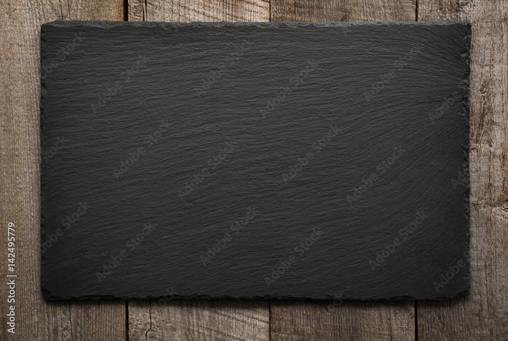 Black slate tile on wooden background. Top view. - obrazy, fototapety, plakaty 