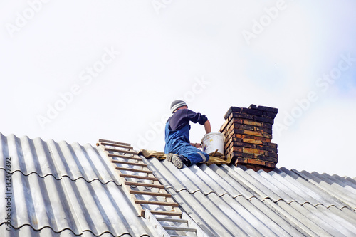 Man makes a masonry of bricks. Roof chimney repair