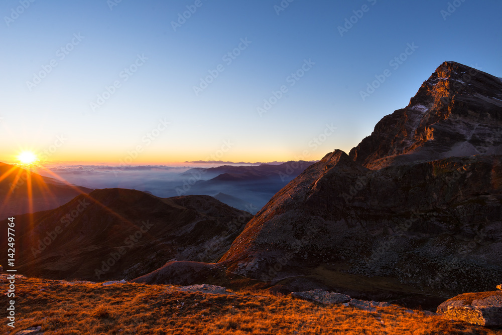 Mountain range at sunset, backlight with sunburst, italian Alps