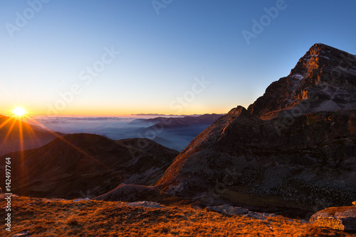 Mountain range at sunset, backlight with sunburst, italian Alps