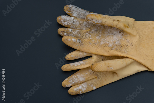 yellow moldy glove on a black background photo