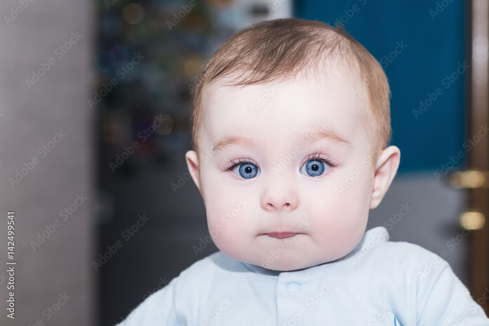 portrait of adorable baby girl / boy with big blue eyes. kid looks into the camera with admiration. happy family concept