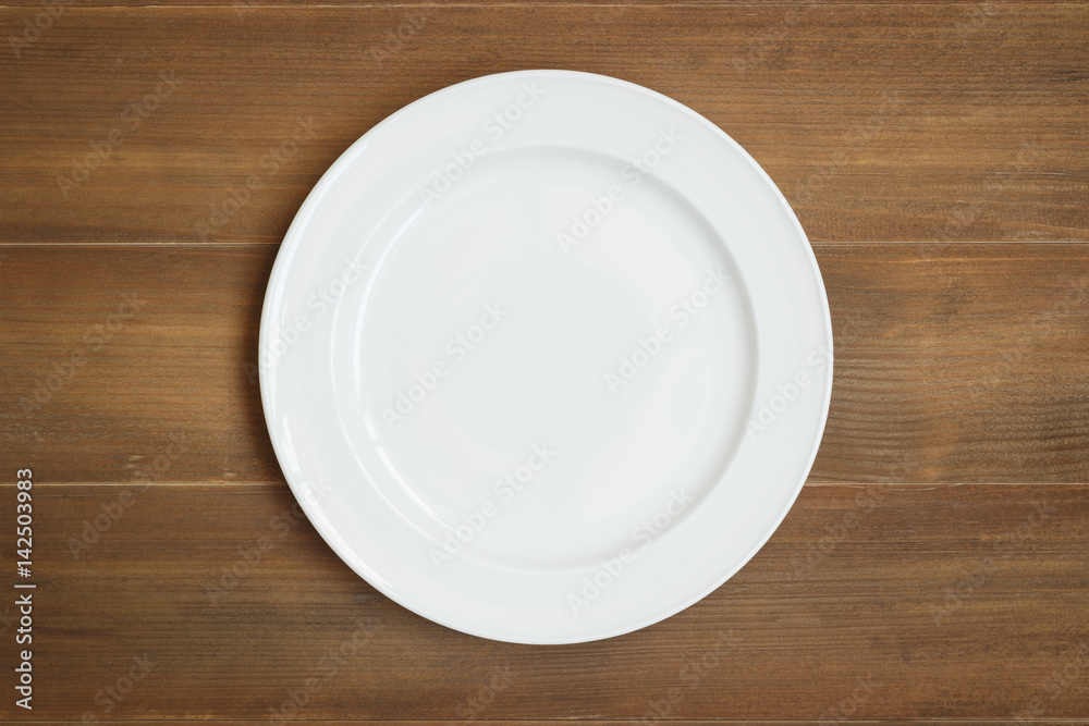 Top view of empty white dish on wooden background