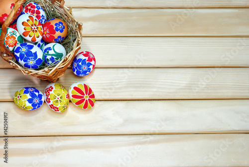 Braided Easter basket with hand-painted eggs on wooden boards