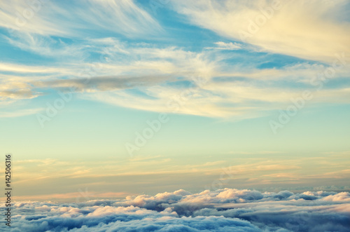 Gold and blue colors clouds abstract background. Sunset sky above the clouds. Universal background in soft pastel colors.