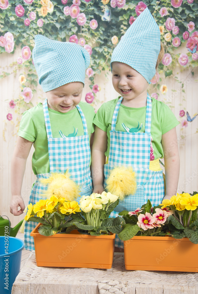 Girl with a pigtail and dress pours from a watering onions in the pan on the windowsill Girl with a pigtail and dress pours from a watering onions in the pan on the windowsill