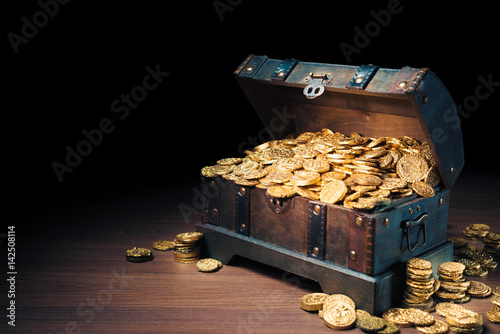 Open treasure chest with gold coins on a dark background