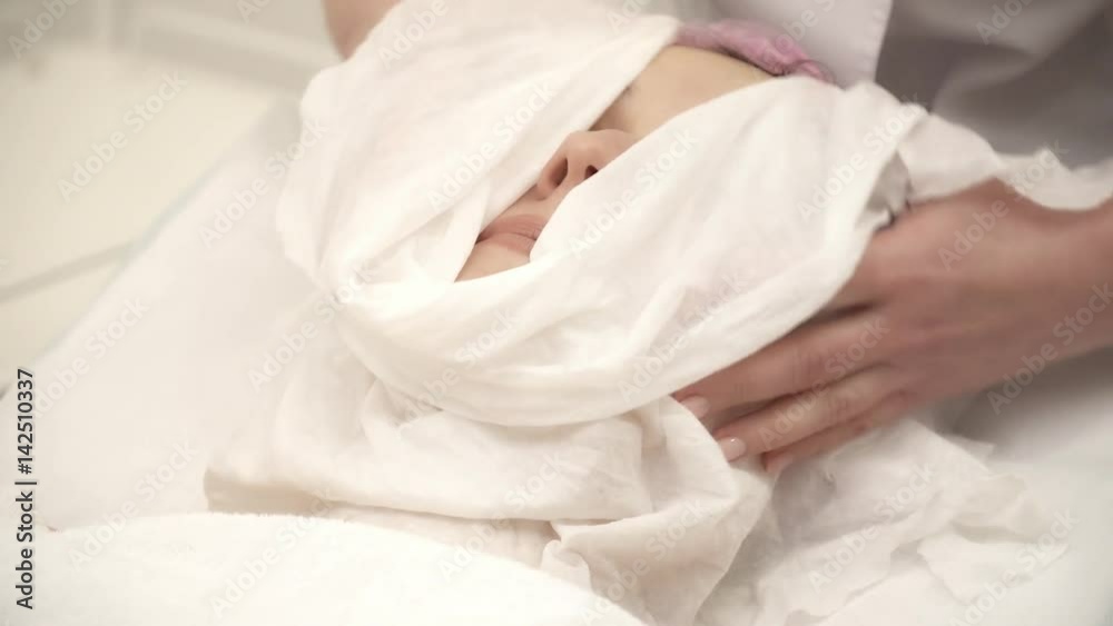 Beautician is clearing a facial anti-aging mask from woman's face