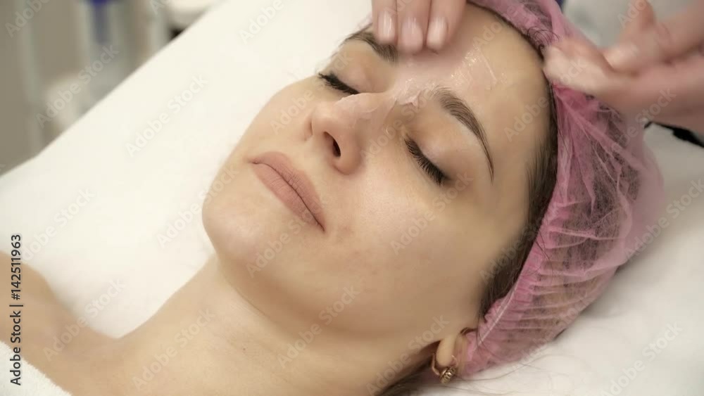 Beautician is applying mask to woman's face Beautician is applying mask to woman's face