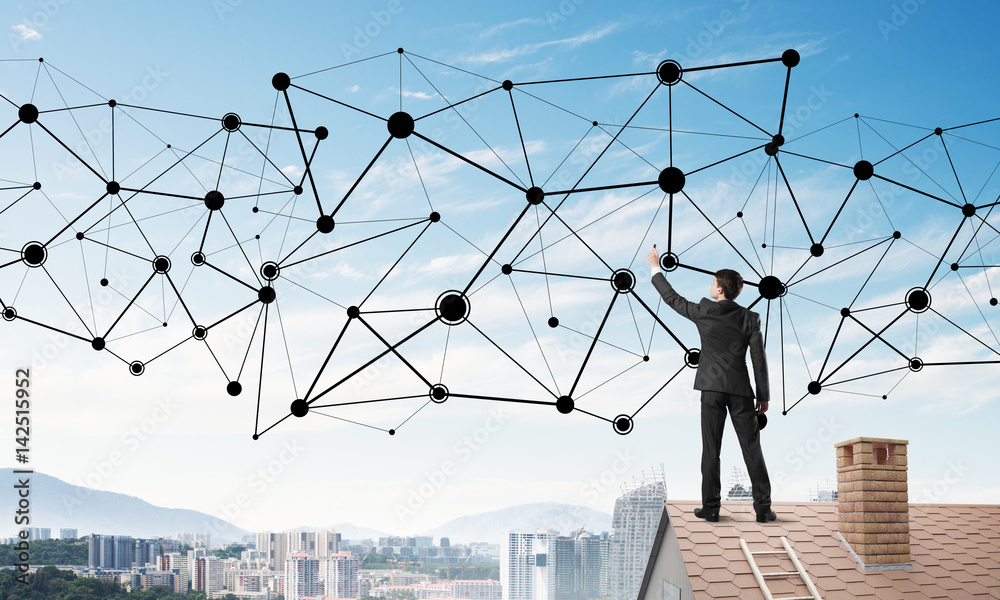 Businessman on house roof presenting networking and connection concept. Mixed media Businessman on house roof presenting networking and connection concept. Mixed media
