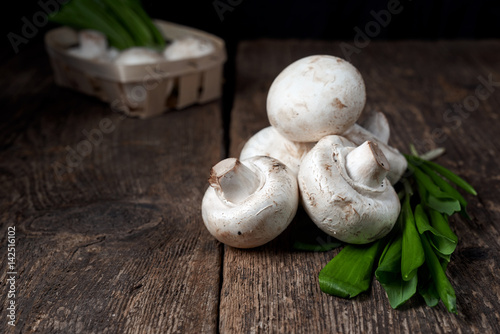 Fresh white mushrooms champignon in brown bowl on wooden background. Top view.