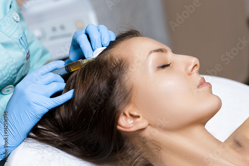 Needle mesotherapy. Cosmetic been injected in woman's head. Thrust to strengthen hair and their growth