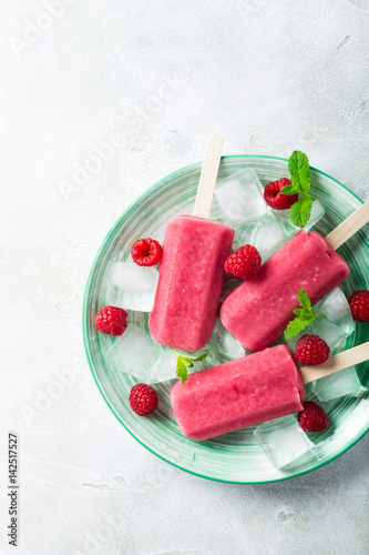 Homemade strawberry popsicles on green plate with ice, strawberries and mint. Healthy summer food concept with copy space. Top view.
