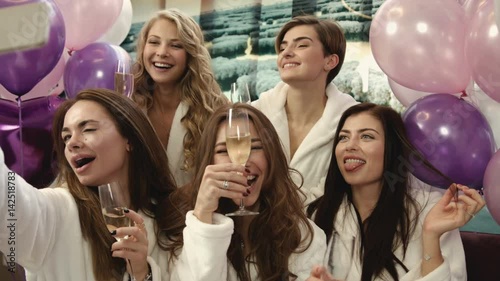 Group of beautiful girls sitting at the beauty salon and taking selfies. Smiling women having good time in spa salon.