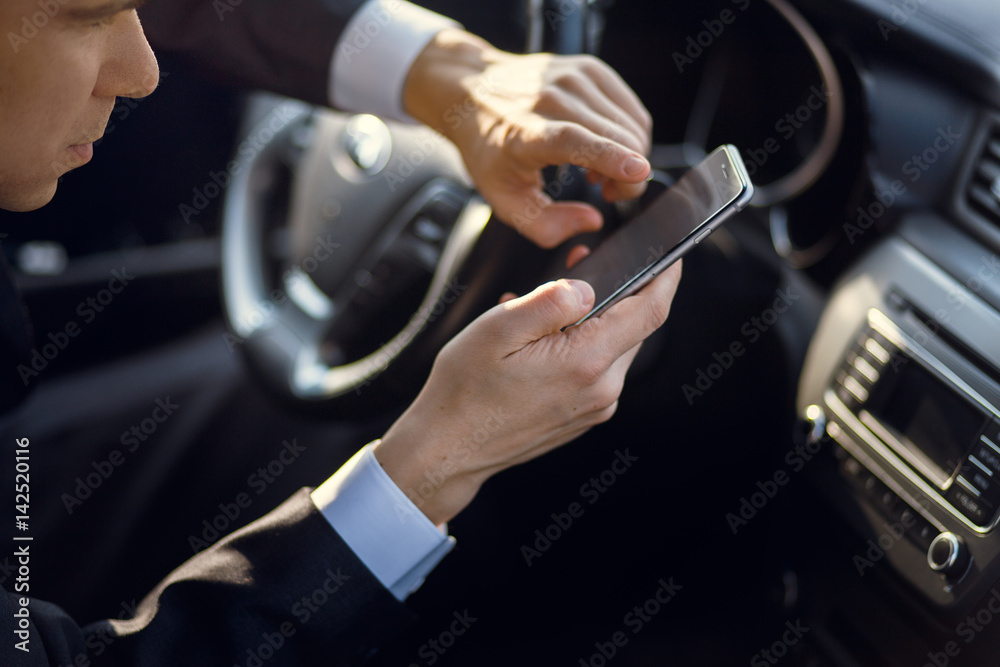 Bussinesman hand with smartphone driving car Bussinesman hand with smartphone driving car