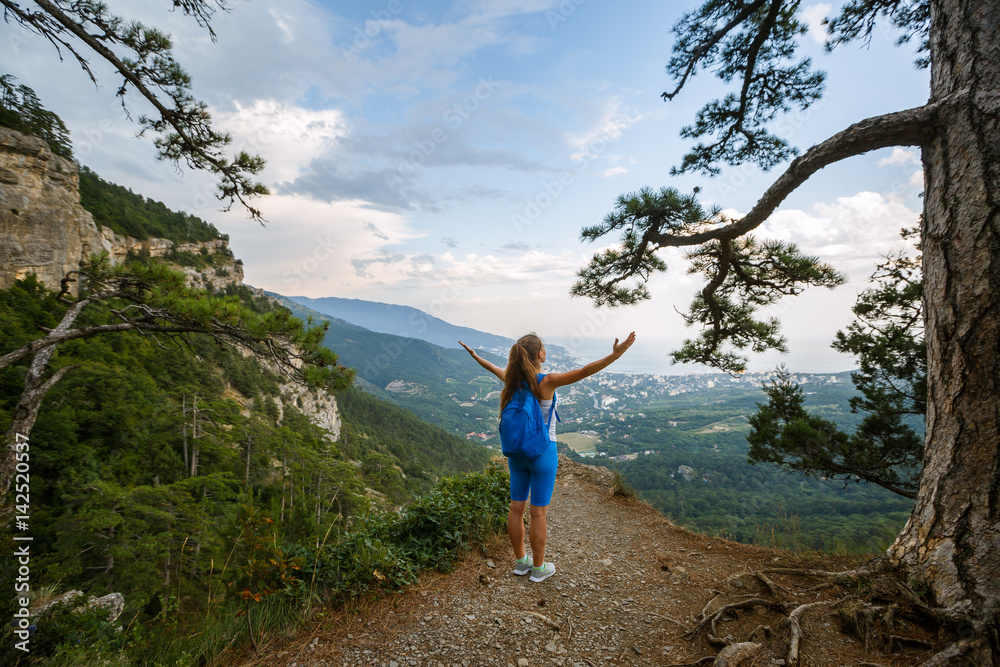 Cheering woman hiker open arms at mountain peak, Young girl spreading hands with joy and inspiration with backpack on, healthy lifestyle and freedom concept