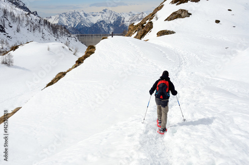 Hiker with snowshoes in winter mountains, Alps, Italy