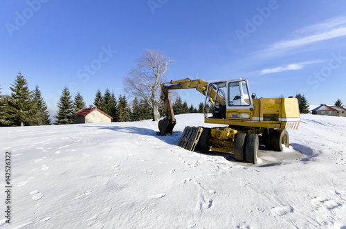construction site digger at winter snow, industrial machinery on building site
