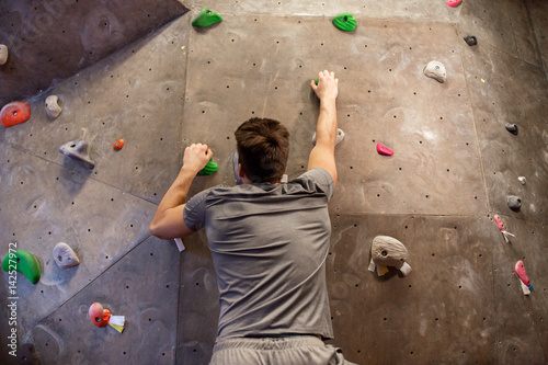 young man exercising at indoor climbing gym wall