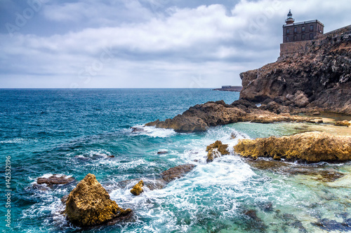 Lighthouse in harbor Melilla, Spanish province in Morocco. The rocky coast of the Mediterranean Sea.