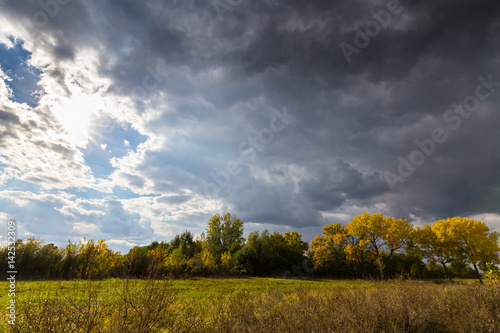 Bright autumn foliage in countryside region and storm clouds, in October