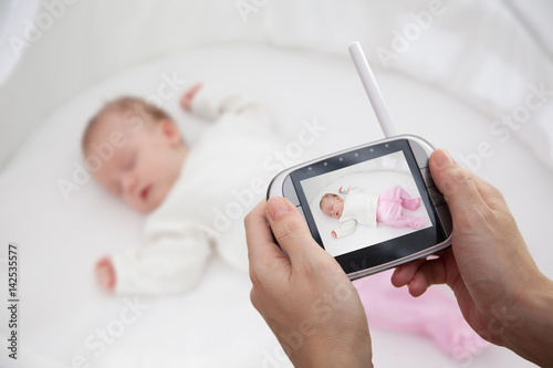 Hand holding video baby monitor for security of the baby