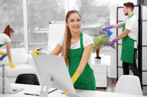 Young female cleaner wiping...