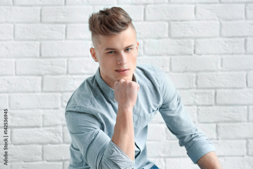 Handsome young man posing on white brick wall background Handsome young man posing on white brick wall background