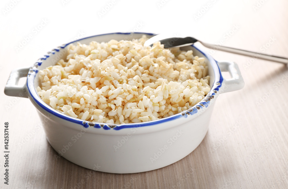 Modern ceramic saucepan full of boiled brown rice on wooden table Modern ceramic saucepan full of boiled brown rice on wooden table