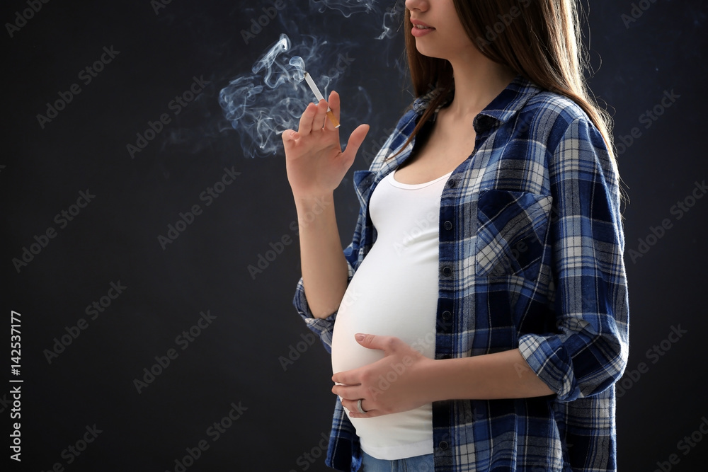 Pregnant woman smoking cigarette on dark background Stock Photo | Adobe Stock