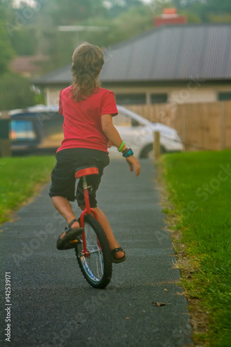 Fototapeta Naklejka Na Ścianę i Meble -  outdoor portrait of young boy riding a unicycle on natural background