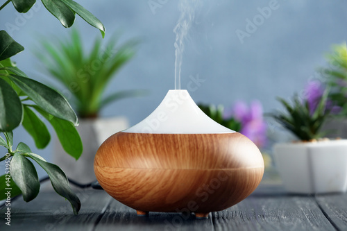Aroma oil diffuser on wooden table photo