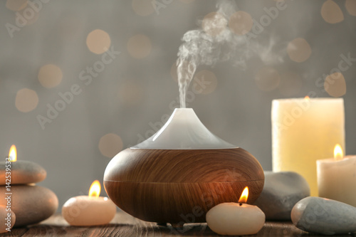 Aroma oil diffuser and candles on blurred background photo