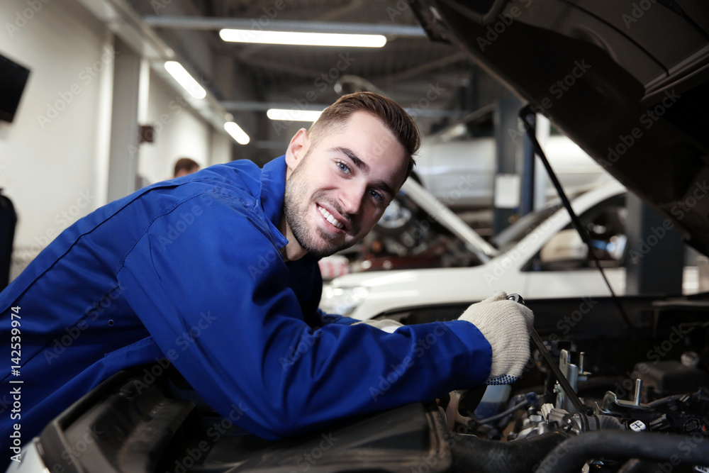 Mechanic repairing car with open hood Mechanic repairing car with open hood