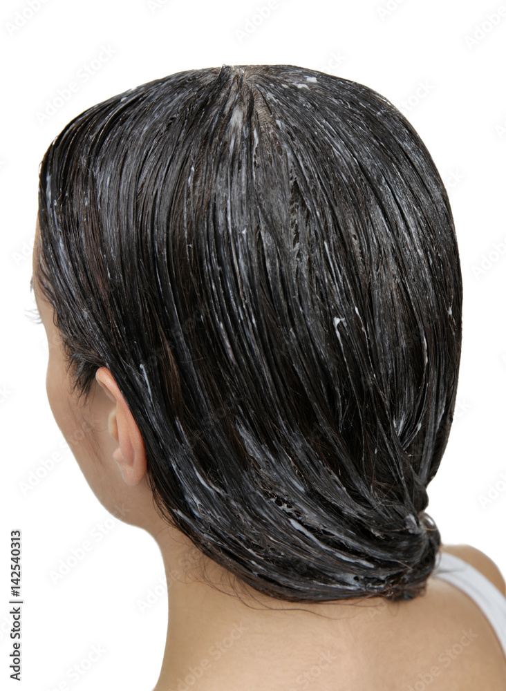Naklejka premium Young woman with coconut oil applied onto hair, on white background
