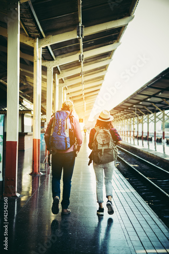 Young attractive hipster couple waiting for the train to go traveling. Travel concept.